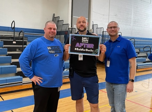  Three male staff pose after their haircuts in the gymnasium